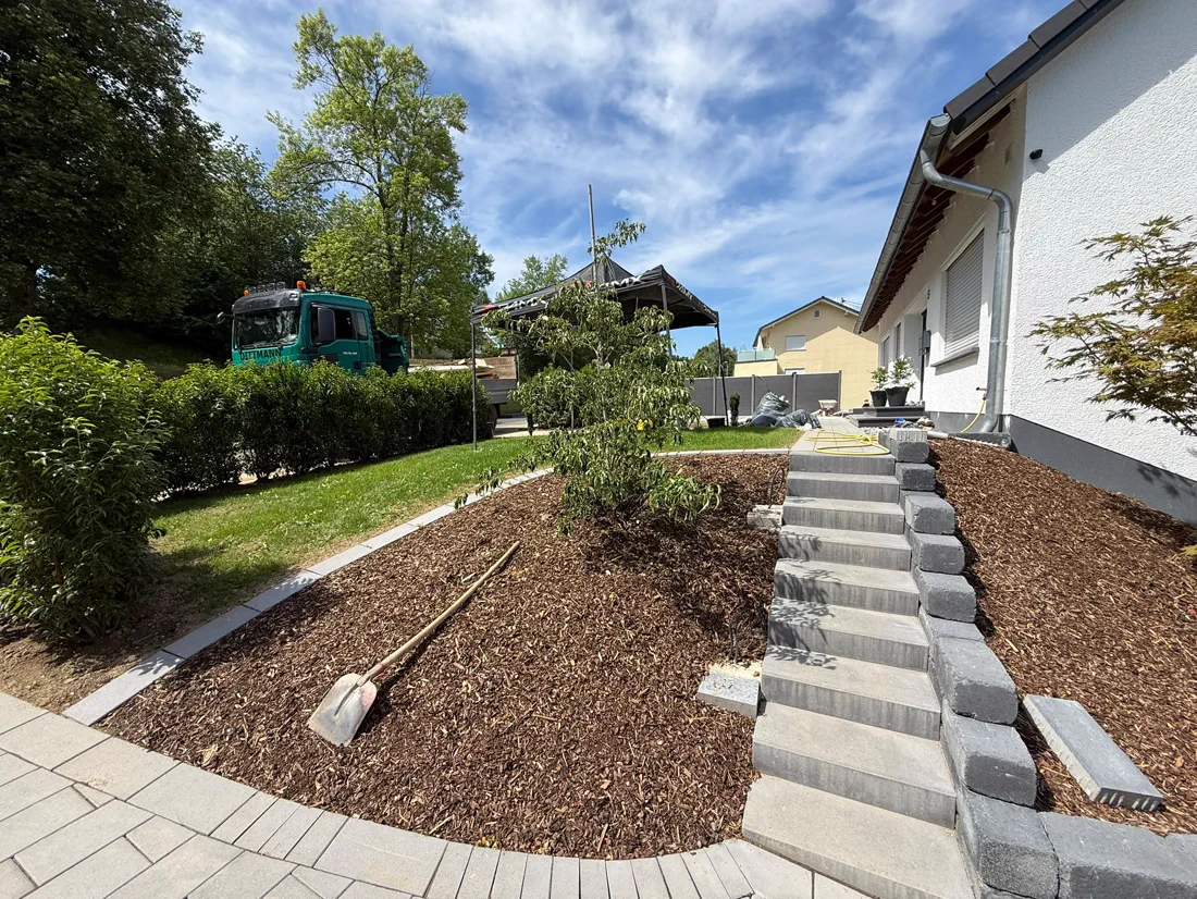 Neu angelegte Böschung mit Rindenmulch und einer Treppe aus Blockstufen neben dem Haus